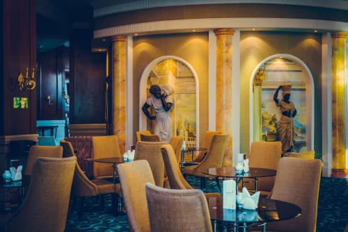 a restaurant with tables and chairs and a statue at Diplomat Hotel by AG Hotels Group in Astana