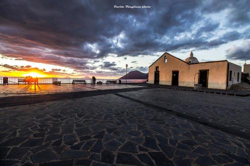 a building on a street with the sunset in the background at "Sweet Life" Casa Vacanze in Lipari