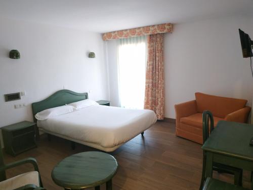 a bedroom with a bed and a chair and a window at Sabiñanigo Camp & Hotel in Sabiñánigo
