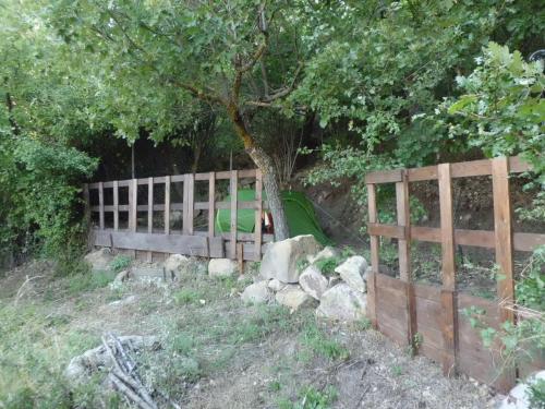 a wooden fence with a tree and a green slide at Casetta dei "Prati" in Vaglio di Basilicata