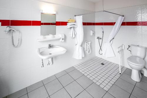 La salle de bains blanche est pourvue d'un lavabo et de toilettes. dans l'établissement Hôtel Galilée Windsor, à Lourdes