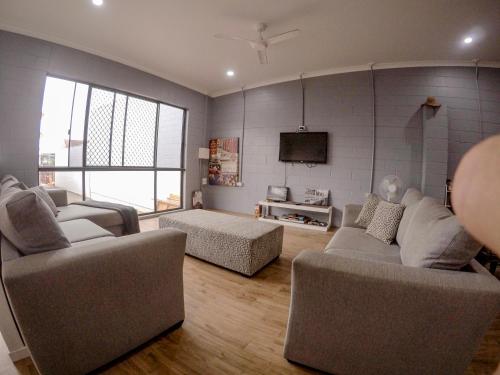 a living room with two couches and a tv at Bunk Inn Hostel in Bundaberg