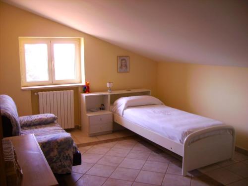 a bedroom with a bed and a window and a chair at Casetta dei "Prati" in Vaglio di Basilicata