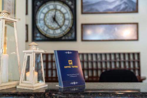 a table with a book and a clock on a wall at Hotel Tatra in Zakopane