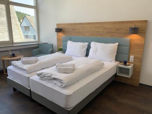een groot bed met witte lakens en kussens erop bij besttime Hotel Monschau in Monschau