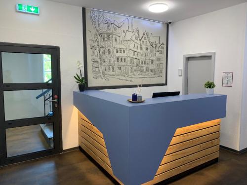 an office with a blue counter with a drawing on the wall at besttime Hotel Monschau in Monschau