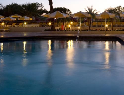 a swimming pool at night with umbrellas at Lagoona by Isrotel Collection in Eilat