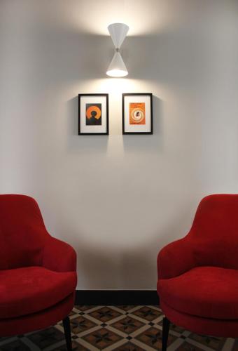 two red chairs sitting next to a white wall at Isabella di Castiglia Apartments in Siracusa
