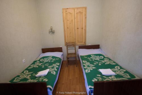 two beds in a room with green and white sheets at Eka&Nino GuestHouse in Mestia