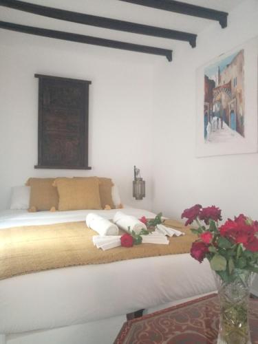 a white bedroom with a bed with red flowers on it at Riad Etoile De Mogador in Essaouira