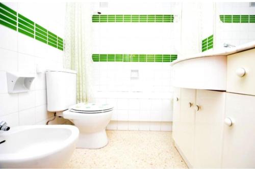 a white bathroom with a toilet and a sink at Apartamento Pineda in Pineda de Mar