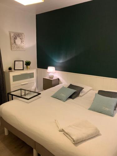 a bedroom with a large white bed with a green wall at Le Louisiane in Soorts-Hossegor