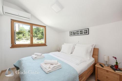 a bedroom with a bed with white sheets and a window at Villa Lubey in Ljubač