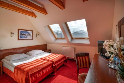 sypialnia z łóżkiem, telewizorem i oknami w obiekcie Hotel Tatra w Zakopanem