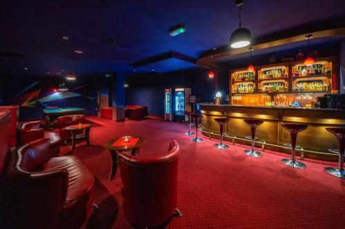 a bar with red carpet and red chairs and tables at Hotel Tatra in Zakopane