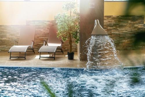 a water fountain in a pool with two chairs at Hotel Tatra in Zakopane