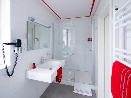 a white bathroom with a sink and a shower at Landhotel Fettehenne in Leverkusen