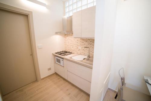 a small kitchen with white cabinets and a sink at kamilia guestrooms in San Cassiano