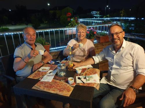 a group of three people sitting at a table with pizza at Locazioni Turistiche By Max in Montegrotto Terme