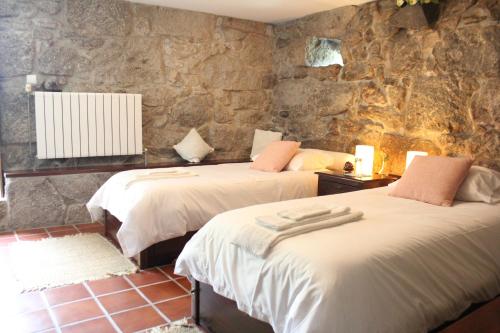 Habitación con 2 camas y paredes de piedra. en Quinta de Favaes, en Paredes de Coura