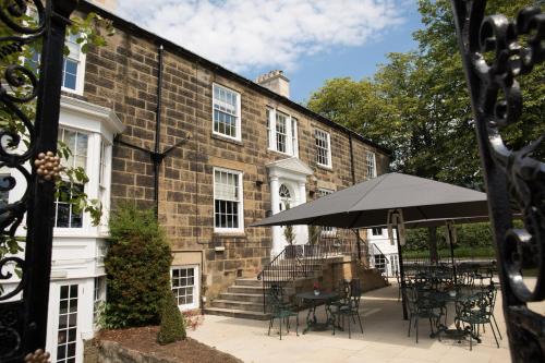 um grande edifício de tijolos com uma mesa e um guarda-chuva em The Cleveland Tontine em Northallerton