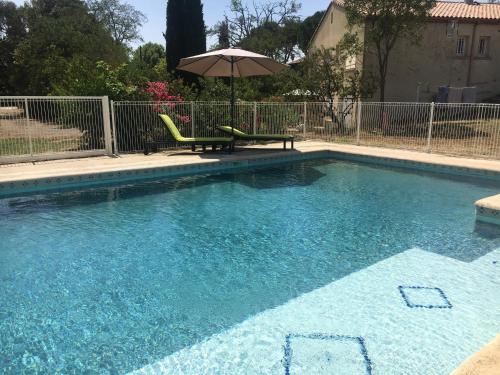 a swimming pool with a chair and an umbrella at Les Gites De La Serre in Saint-Thibéry