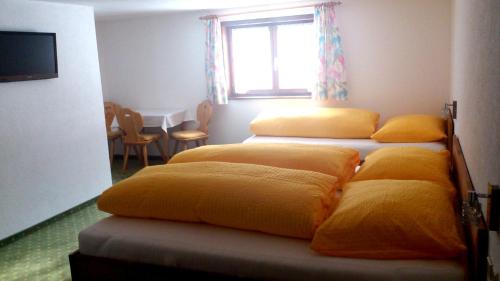 a room with four beds with yellow pillows at Frühstückspension Gweil in Sankt Gallenkirch