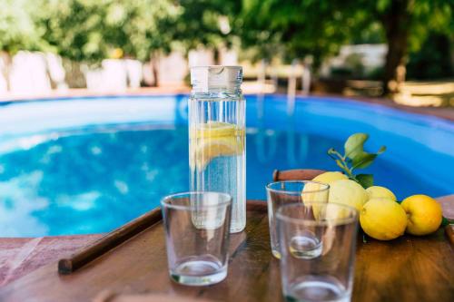 a bottle of water and glasses on a table near a pool at Cortijo Abril in Priego de Córdoba