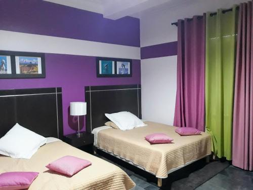 2 łóżka w pokoju z fioletowymi i zielonymi ścianami w obiekcie RESIDENCE Paradise w mieście Fort de lʼEau