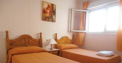 Un dormitorio con dos camas y una ventana. en ApartRoquetas, en Roquetas de Mar