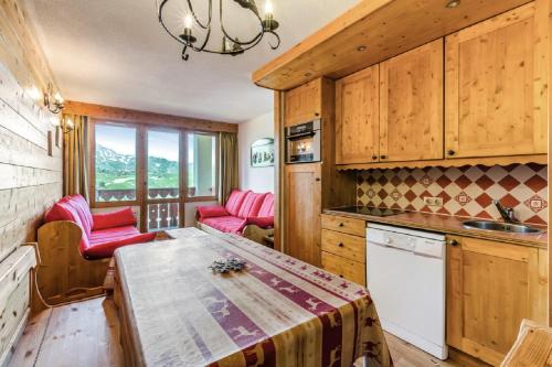 une cuisine avec des armoires en bois et une table et des chaises dans l'établissement Residence Les Constellations - maeva Home, à Belle Plagne
