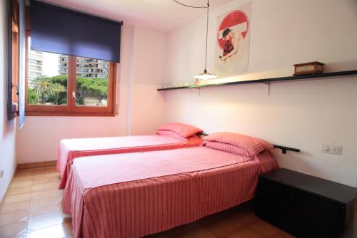 2 Betten in einem Schlafzimmer mit rosa Bettwäsche und einem Fenster in der Unterkunft Tamarius 1-7 in Platja  d'Aro