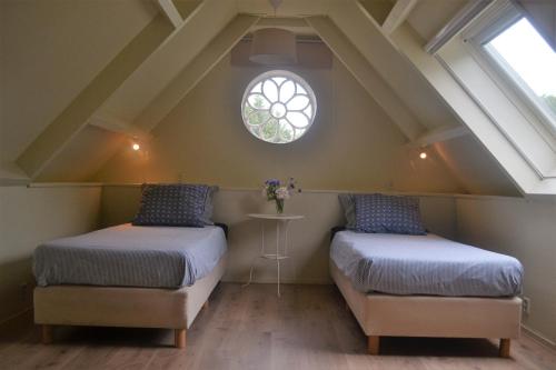 two beds in a attic room with a window at Het Friese Huisje in Boazum