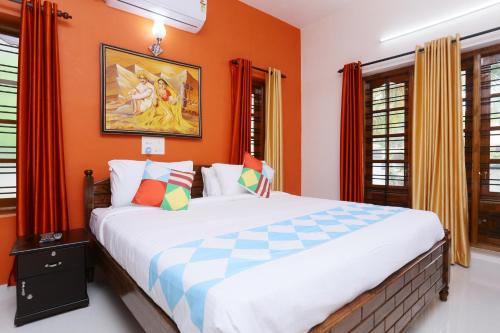 a bedroom with a large bed with orange walls at Belhaven Home Stay in Trivandrum