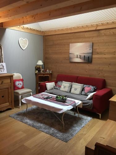 a living room with a red couch and a table at La Maison des Coeurs in Attignat-Oncin
