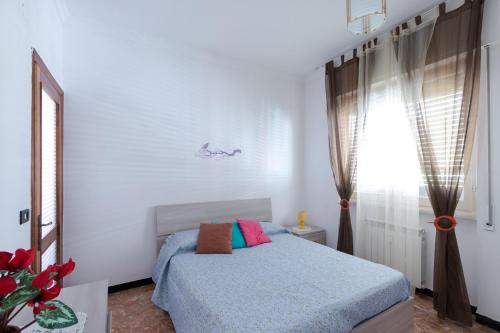 a white bedroom with a bed and a window at House Henry in Vado Ligure
