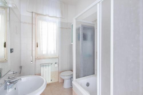 a white bathroom with a toilet and a sink at House Henry in Vado Ligure