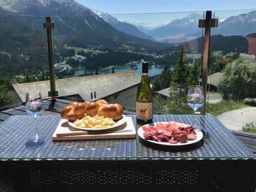 a table with two plates of food and a bottle of wine at Chalet Casa Cresta - Top of Lenzerheide - bis 8 Personen in Valbella