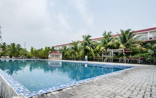 een groot zwembad met palmbomen en een gebouw bij Hotel Sonar Bangla Kolaghat in Bāgnān
