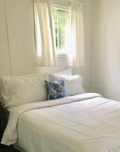a bed with white sheets and pillows with a window at Beachside on Lake Muskoka in Port Carling