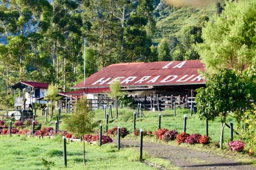 a building with a red roof in a field at La Herradura lodge in Santa Rosa de Cabal