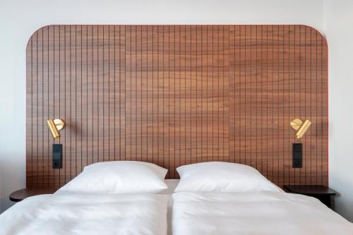 two beds in a room with a large headboard at Vienna House by Wyndham Amber Baltic Miedzyzdroje in Międzyzdroje