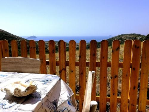 a wooden fence with a table in front of the ocean at Agriturismo Glamping Erbe Matte in SantʼAntìoco