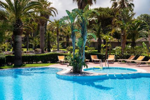 una piscina con sillas y palmeras en un complejo en Baia Del Sole Resort, en Capo Vaticano