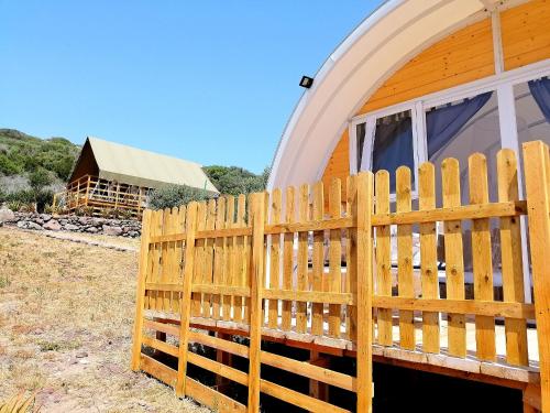 a wooden fence in front of a house at Agriturismo Glamping Erbe Matte in SantʼAntìoco