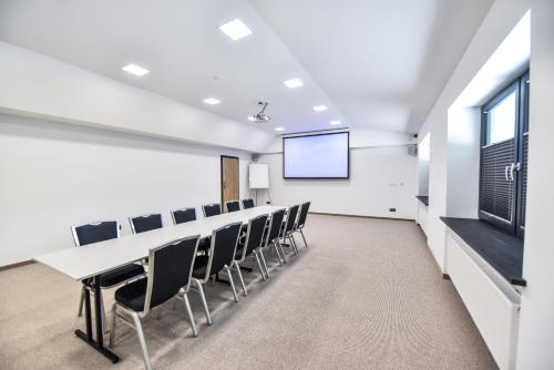 a conference room with a table and chairs and a screen at Sport Rooms Spała in Spała