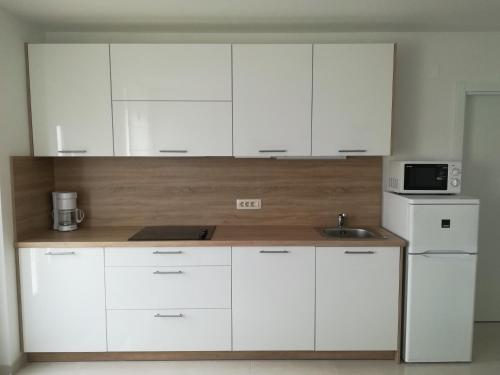 a kitchen with white cabinets and a sink and a microwave at Apartman Ana in Porat