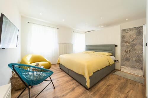 ein Schlafzimmer mit einem Bett und einem blauen Stuhl in der Unterkunft Impression in Mošćenička Draga