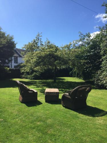 dwa krzesła siedzące w trawie na dziedzińcu w obiekcie Kilmory House w mieście Lochgilphead