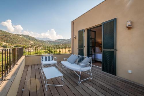 a patio with two chairs and a table on a deck at Hôtel Restaurant Villa Joséphine in LʼÎle-Rousse